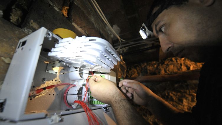Un homme installe la fibre dans un immeuble à Paris. (BERTRAND LANGLOIS / AFP)